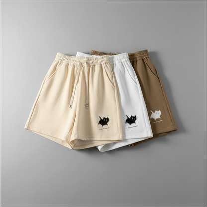 Three pairs of shorts in beige, white, and brown with cat illustrations on a gray background.