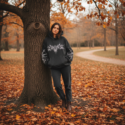 a dark over sized hoodie with a white design, standing in an autumn park.